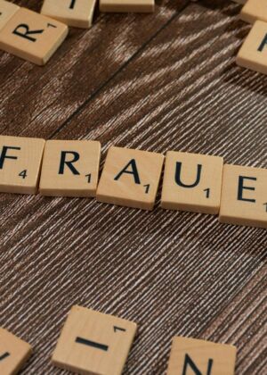 Close-up of wooden tiles spelling 'Frauen' on a wooden surface, high angle.
