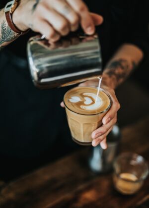 man pouring milk in coffee