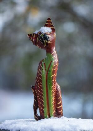 a statue of a cat sitting on top of snow covered ground