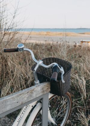 a bicycle parked on a wooden rail near a beach