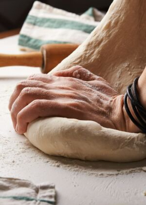 person making dough beside brown wooden rolling pin
