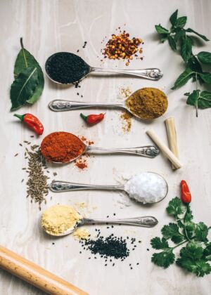five gray spoons filled with assorted-color powders near chilli