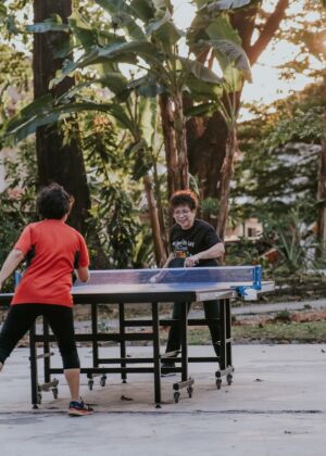 man in red crew neck t-shirt standing beside blue table during daytime